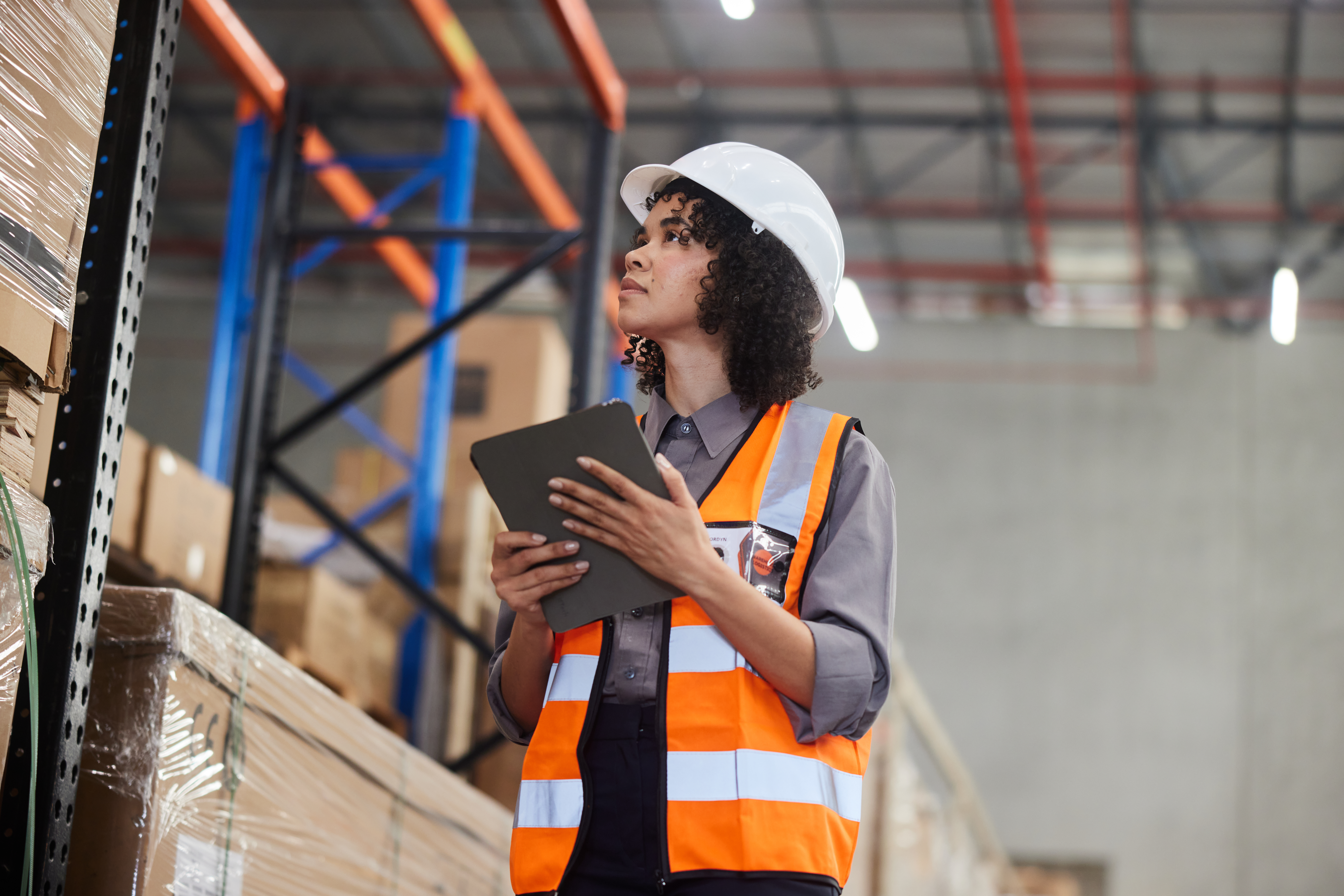 Female engineer tracing shipments with a tablet in a large distribution warehouse